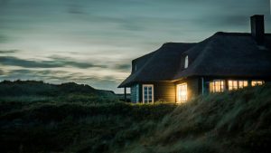 Ein Haus im Dämmerlicht umgeben von grünem langen Gras